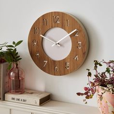 a wooden clock sitting on top of a white shelf next to a potted plant