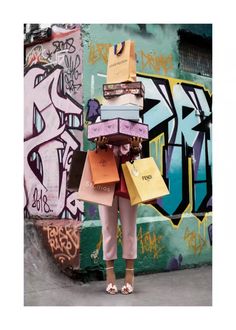 a woman standing in front of a wall with lots of bags on her head