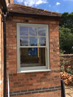 a brick building with a white window and blue sky reflected in the window pane