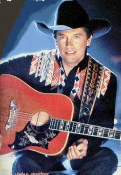 a man wearing a cowboy hat and holding a guitar