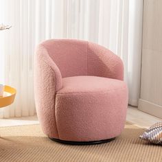 a pink chair sitting on top of a rug next to a window