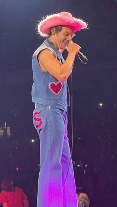 a man with a pink hat on top of his head and microphone in his hand