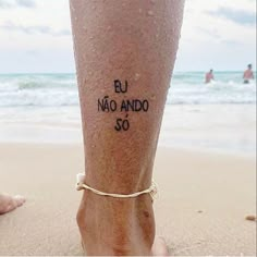 a person's foot with writing on it and the beach in the background,