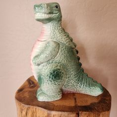 a ceramic dinosaur sitting on top of a wooden stump