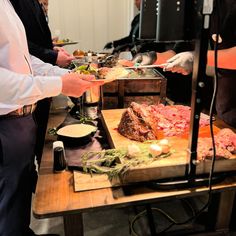 people are serving themselves food at a buffet