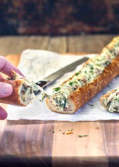 a person is holding a piece of bread with cheese and spinach spread on it