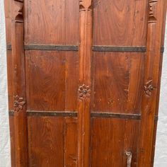 an old wooden armoire with carvings on the top and bottom panel, sitting in front of a white wall