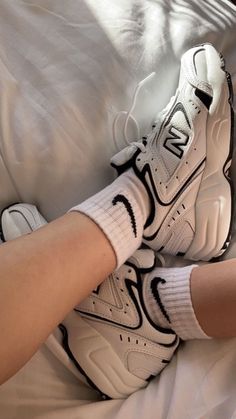 a person wearing white sneakers and socks laying on a bed