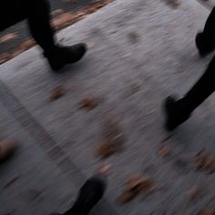 two people walking down the street with their feet in the air and one person wearing black shoes