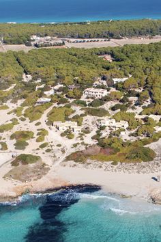 an aerial view of the beach and ocean with houses in the distance, surrounded by trees