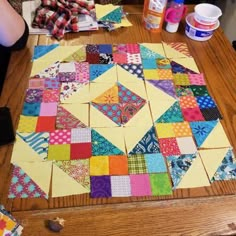 someone is making a quilt on top of a wooden table with scissors and other crafting supplies