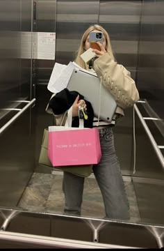 a woman taking a selfie with her cell phone and shopping bags in front of her