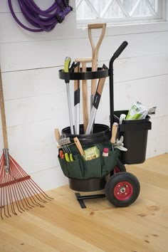 a garden tool holder sitting on top of a hard wood floor next to a broom and rake