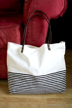 a black and white bag sitting on top of a wooden floor next to a red chair