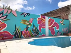 a pool in front of a painted wall with birds and flowers