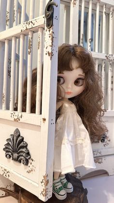 a doll is sitting on the ground in front of a white crib with an open door