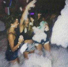 some people are dancing and having fun in the water at a club or party with white streamers all around them