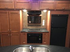 an rv kitchen with stainless steel sink and black refrigerator freezer, stove and dishwasher