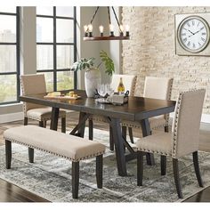 a dining room table and chairs with a clock on the wall in the back ground