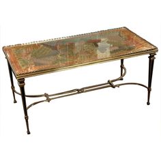 a glass and metal coffee table with an ornate design on it's top, against a white background