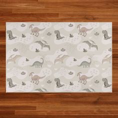 an area rug with dinosaurs and other animals on the wood floor in front of a wooden wall