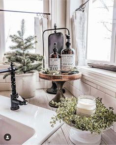 a bathroom sink sitting under a window next to a counter top with bottles on it