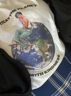 a t - shirt with the image of a man sitting on top of a globe