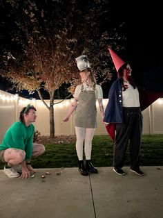 three people dressed in costumes standing on a sidewalk