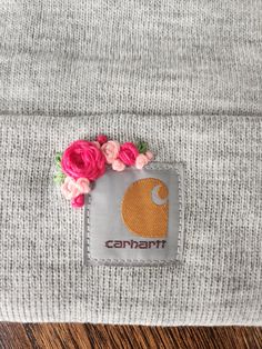 a gray beanie with pink flowers on the front and an elephant patch in the middle