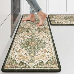 a woman standing on the kitchen floor in front of two rugs that are both green and beige