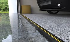 a car is parked in front of a building with water on the ground and yellow lines