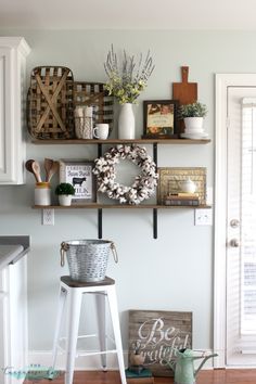 some shelves with baskets and wreaths on them in a room that is painted white