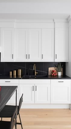 a kitchen with white cabinets and black counter tops