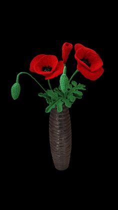 three red flowers are in a vase on a black background with green stems and leaves