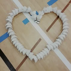 a heart made out of white paper sitting on top of a wooden floor