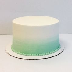 a white and green ombreed cake with beaded trimmings on a plate