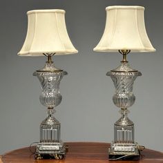 two glass lamps sitting on top of a wooden table next to each other with a white lamp shade