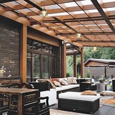 an outdoor living area with couches, tables and lamps on the ceiling is covered in wood slats