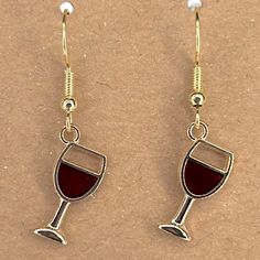 pair of wine glasses dangling from gold - plated earwires on brown background