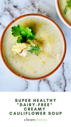 two bowls filled with creamy cauliflower soup on top of a white marble counter