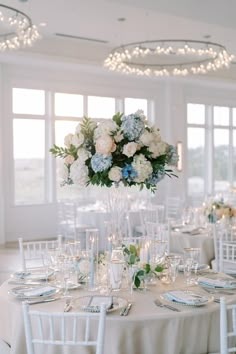 a table set up with white and blue flowers