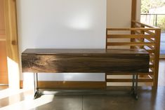 a wooden bench sitting in the middle of a room next to a stair case and window