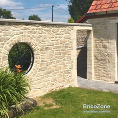 a stone building with a round window on the side and grass in front of it