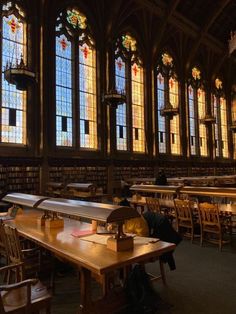 a library with tables and chairs in front of large stained glass windows on the wall