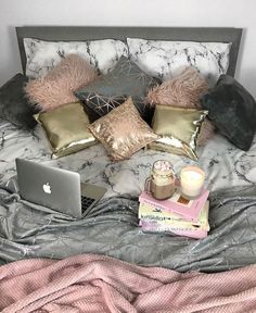 a laptop computer sitting on top of a bed next to pillows and other items in front of it