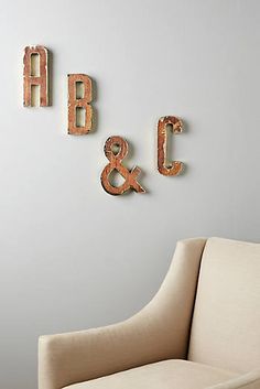 two wooden letters are mounted on the wall above a chair and sofa in a room