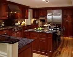 a large kitchen with wooden cabinets and granite counter tops, along with stainless steel appliances