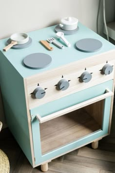 an old fashioned wooden toy stove with plates and utensils on it