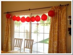 a dining room with red balloons hanging from the ceiling and curtains on the windowsill