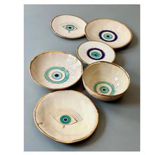 five bowls with blue and white designs on them, one has an evil eye in the center